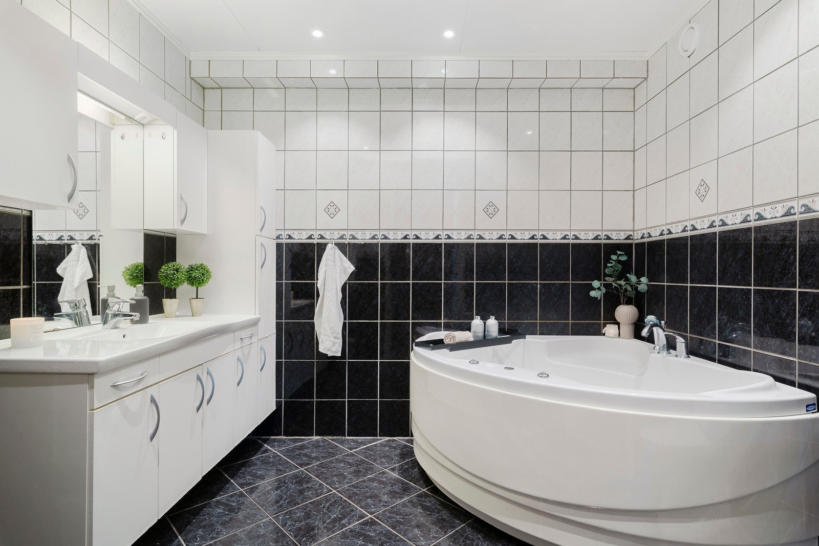 Badet i underetasjen er helfliset med et hjørne-boblebadekar og baderomsinnredning. Galleribilde