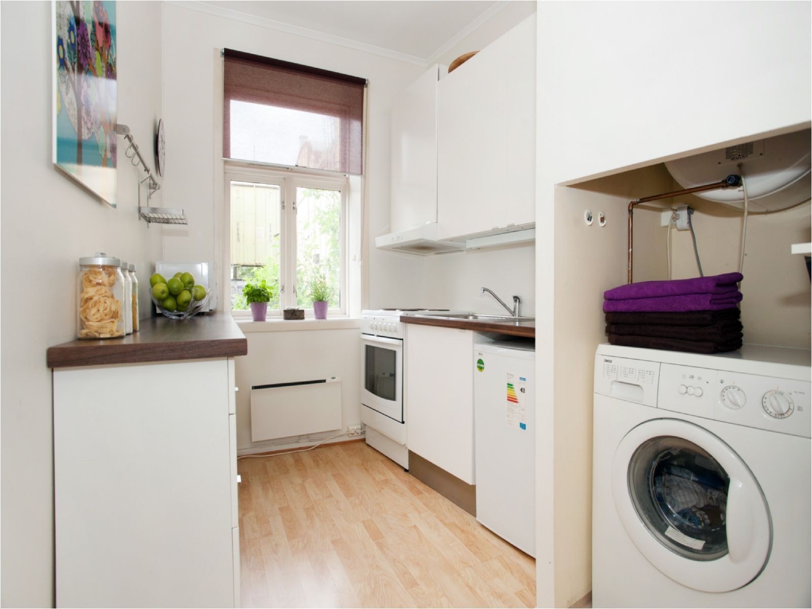 Praktisk løsning med vaskemaskin ved kjøkkeninnredningen. Vindu ut mot bakgård. Galleribilde