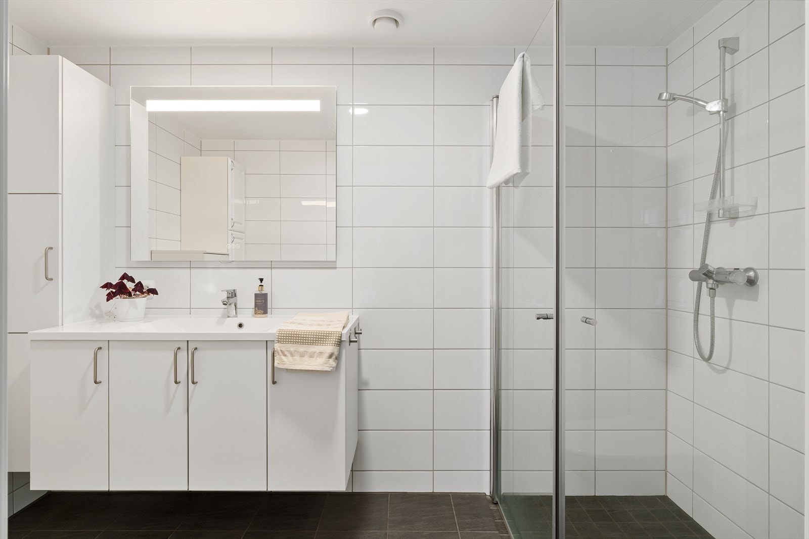 Lekkert og helfliset bad med tidløs hvit innredning og ekstra høyskap. Galleribilde