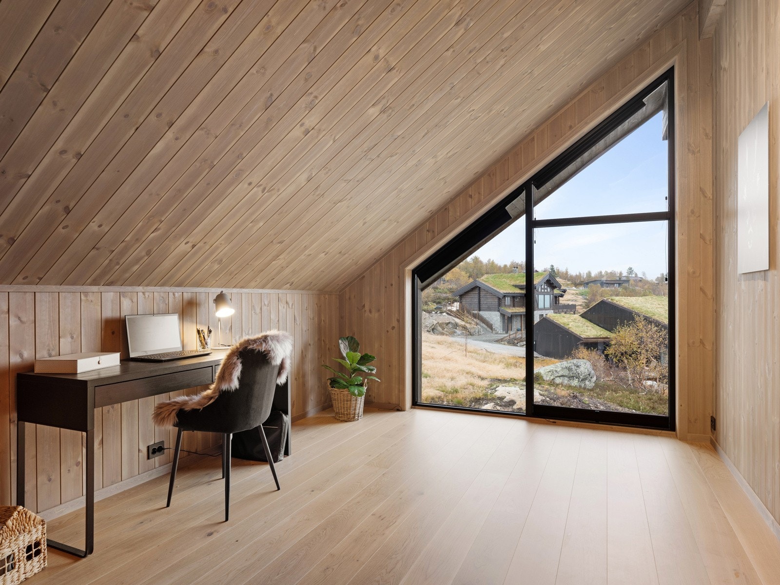 Loftstuen har ekstra takhøyde og store vinduer med utsikt over det nydelige fjellandskapet Galleribilde