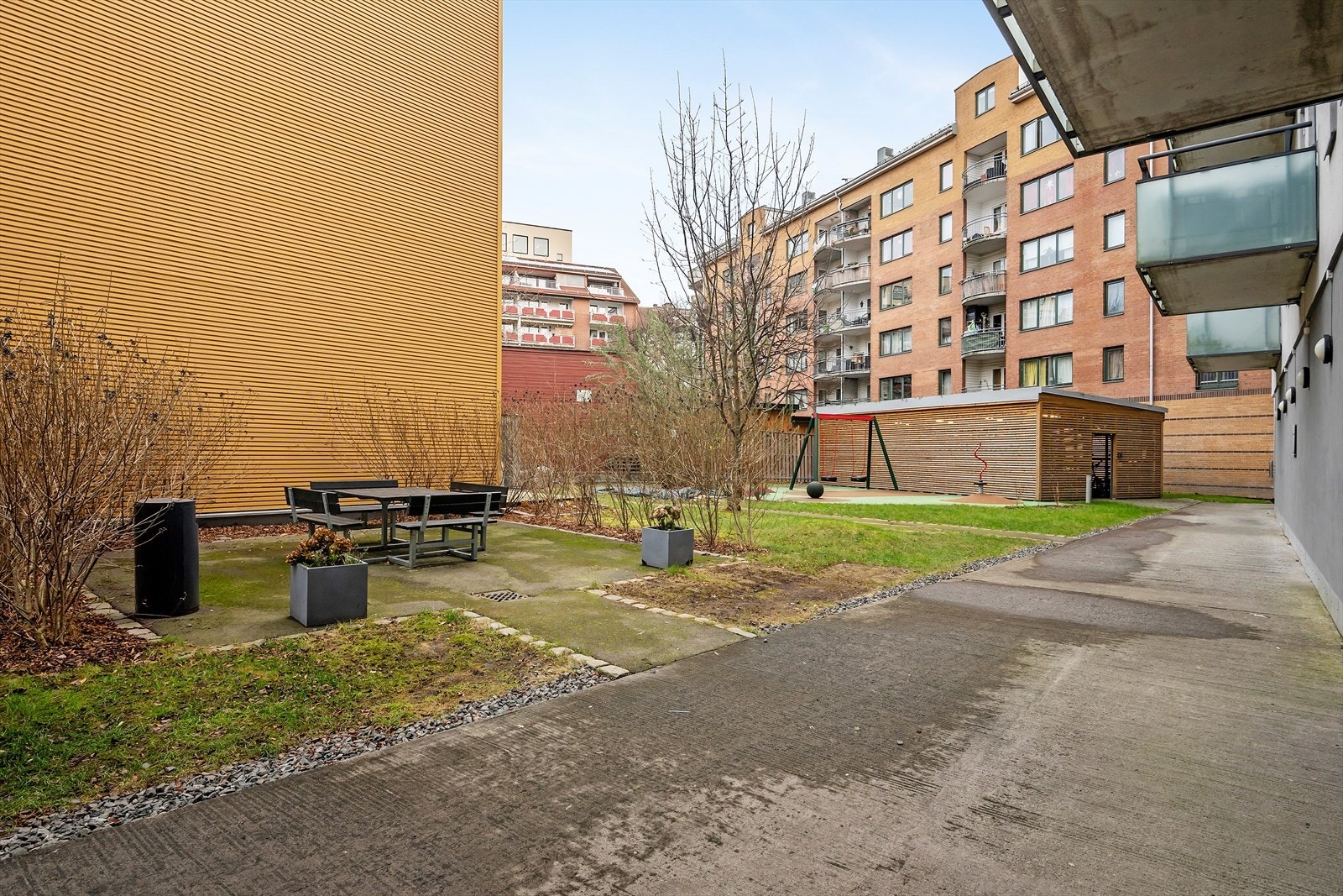 Bakgård med sittegrupper, sykkelskur, lekeplass og beplantning Galleribilde