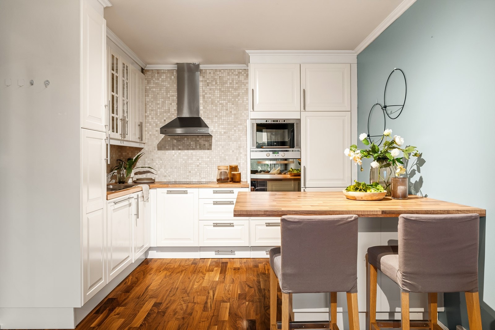 Kjøkkeninnredningen har en tidløs utførelse med hvite, profilerte fronter og benkeplate av laminat. Galleribilde