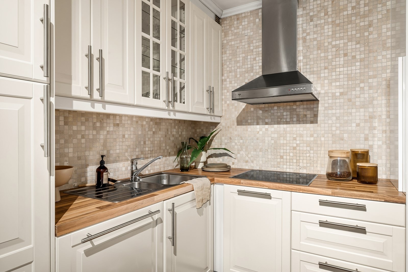 Veggen over benkeplaten er kledd med mosaikkfliser og skaper en fin atmosfære på kjøkkenet. Galleribilde