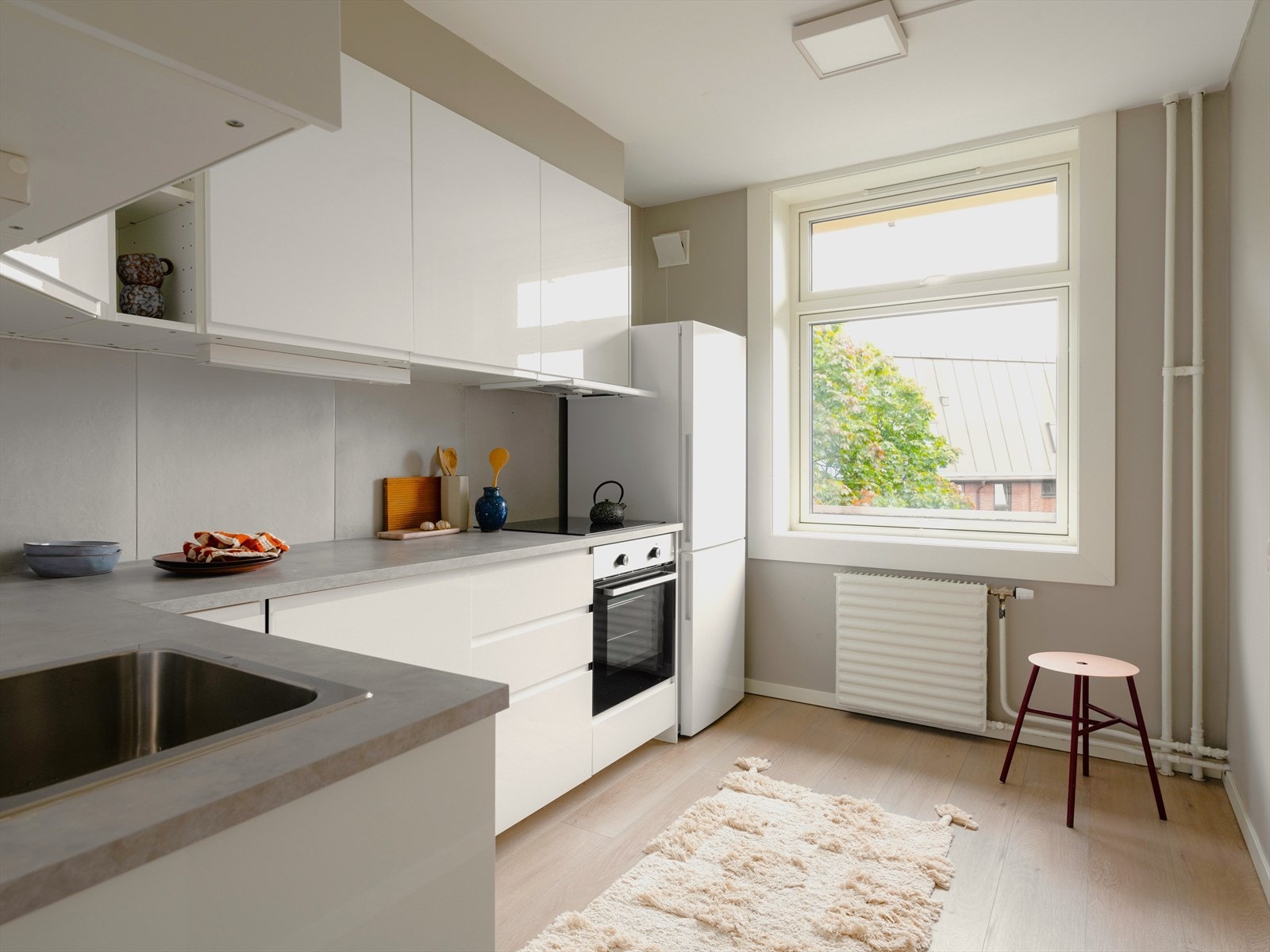 Tidsriktig kjøkken med glatt innredning fra IKEA. Hvitevarene er integrerte, herunder oppvaskmaskin, stekeovn og platetopp. Frittstående kjøleskap med fryserdel. Galleribilde