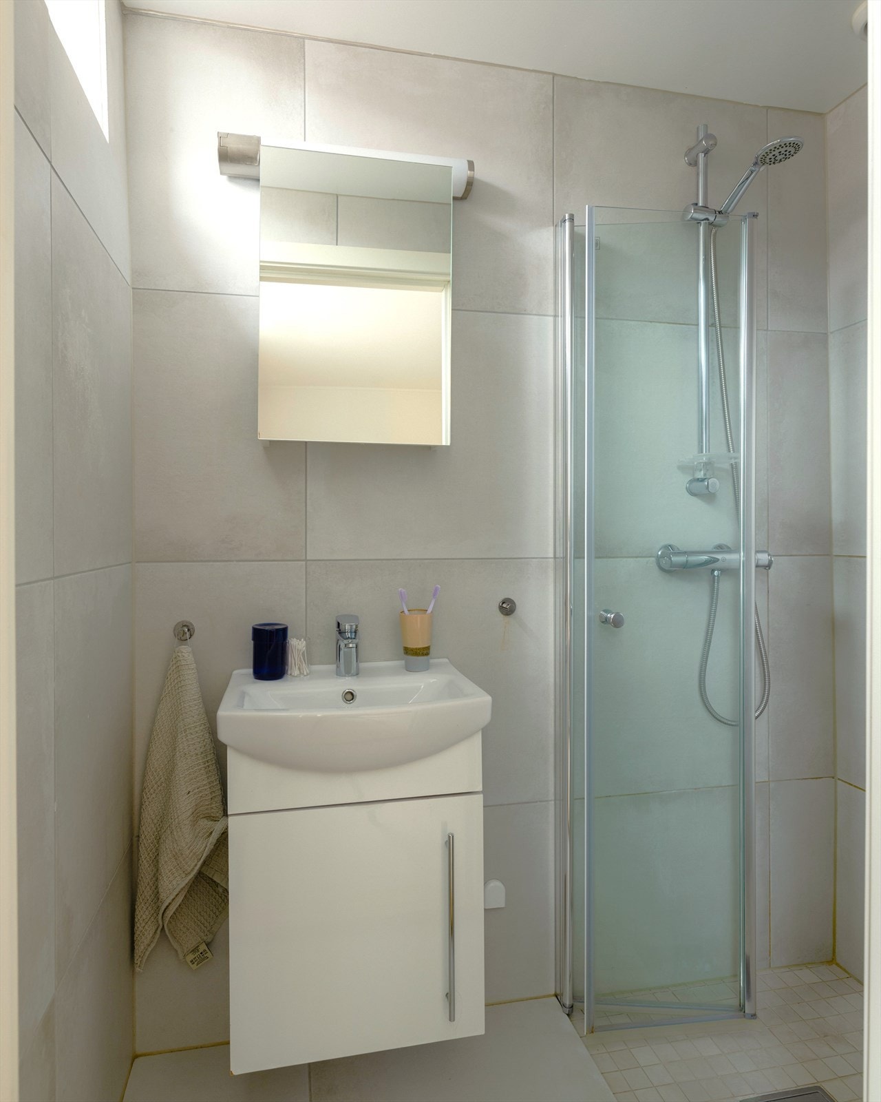 Bad med tidløse fliser, servant, dusjhjørne og varmekabler i gulv. Galleribilde