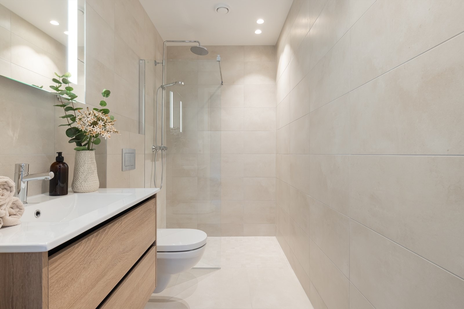 Badet er utstyrt med vegghent WC med dempesete, servantinnredning fra Korsbakken, speil med integrert lys over servant og dusjvegger fra Viking bad med regnfallsdusj og hånddusj. Galleribilde