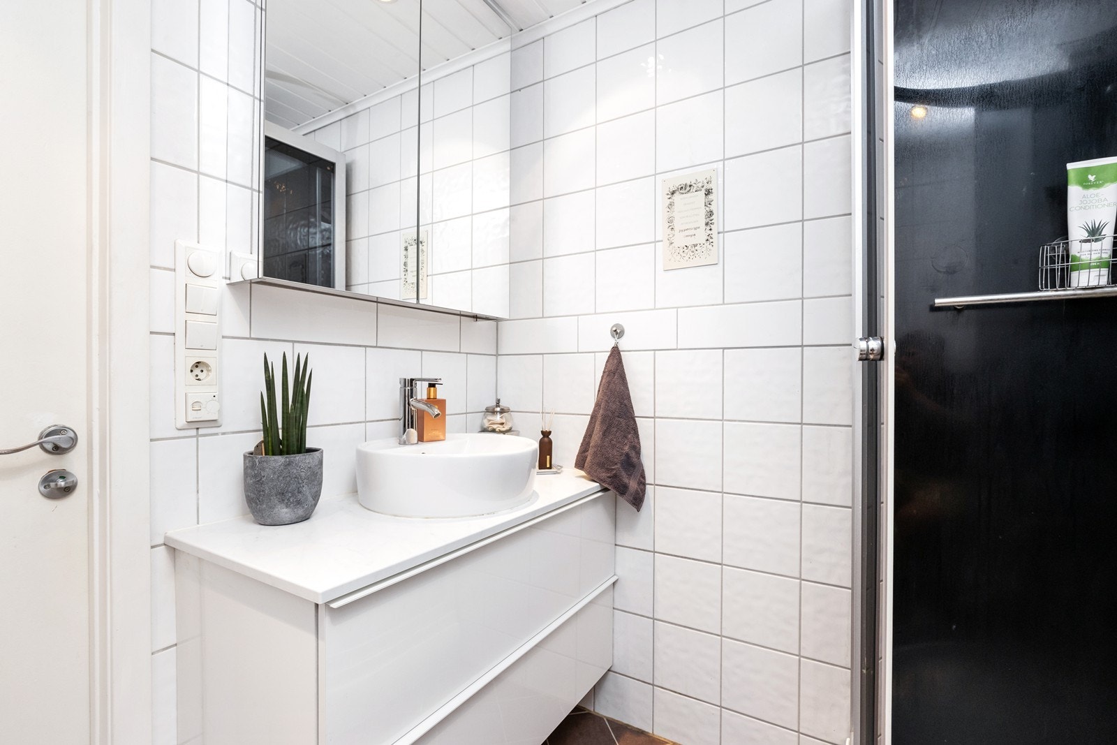Bad i 2.etasje med flislagte overflater og varme i gulv. Badet er innredet med skuffeinnredning med overliggende servant på benk, speilskap på vegg, dusjkabinett og vegghengt toalett. Galleribilde