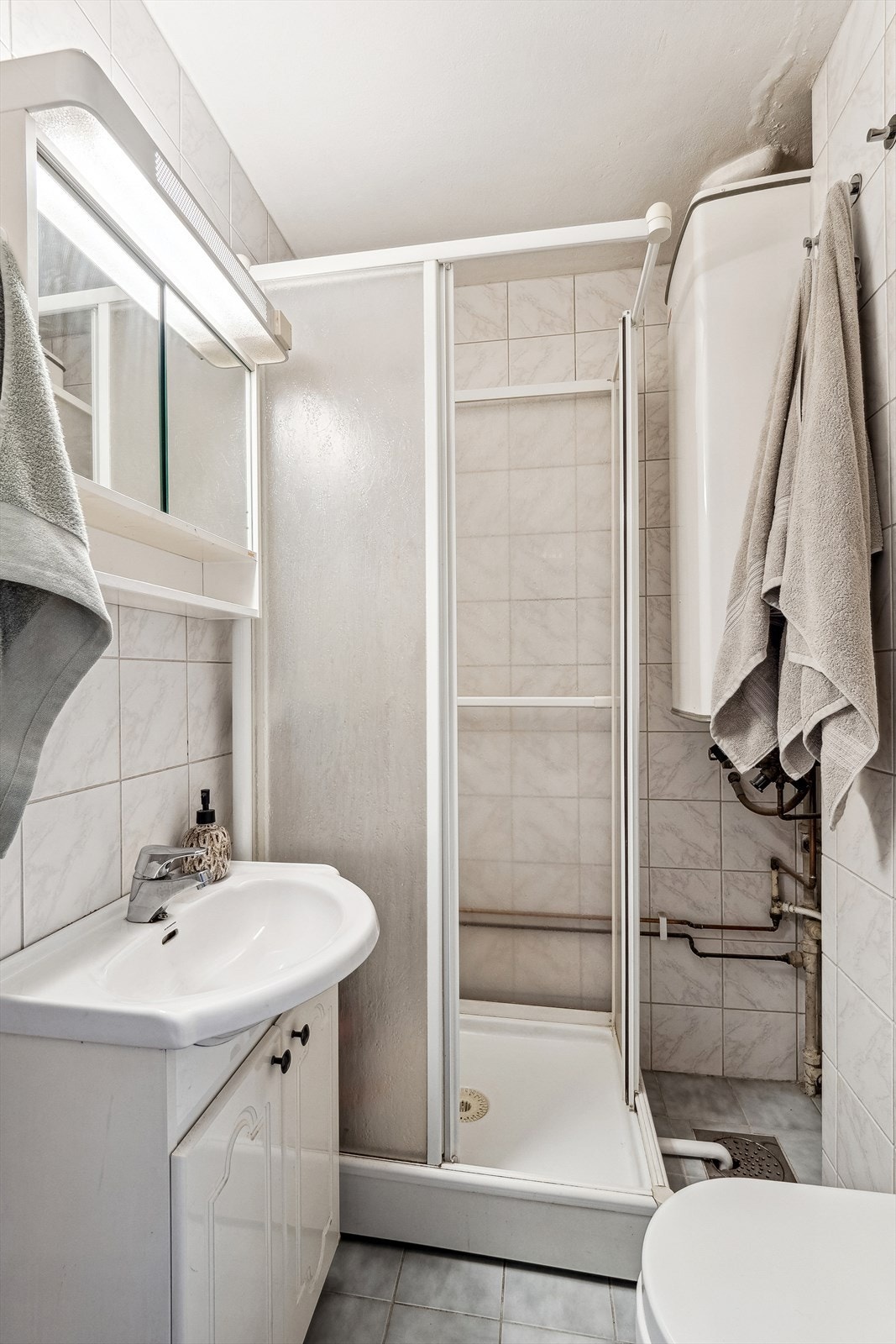 Flislagt bad av ukjent alder. Det er elektriske varmekabler Galleribilde