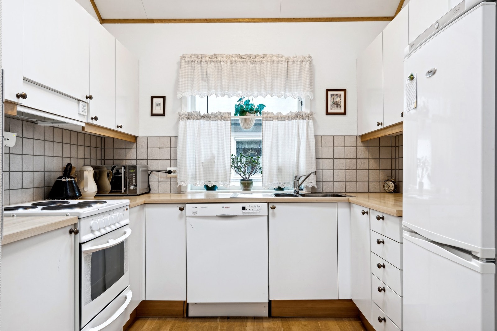 Kjøkkenet har innredning med hvitmalte glatte fronter og benkeplaten er av laminat med dobbel vaskekum Galleribilde