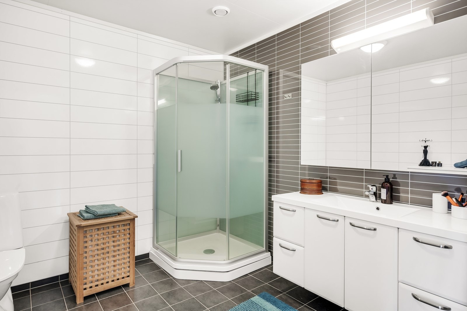 Badet er tidsriktig kledd med flis på gulv med varmekabler, våtromsplater på vegg, og har hvite himlingsplater. Galleribilde