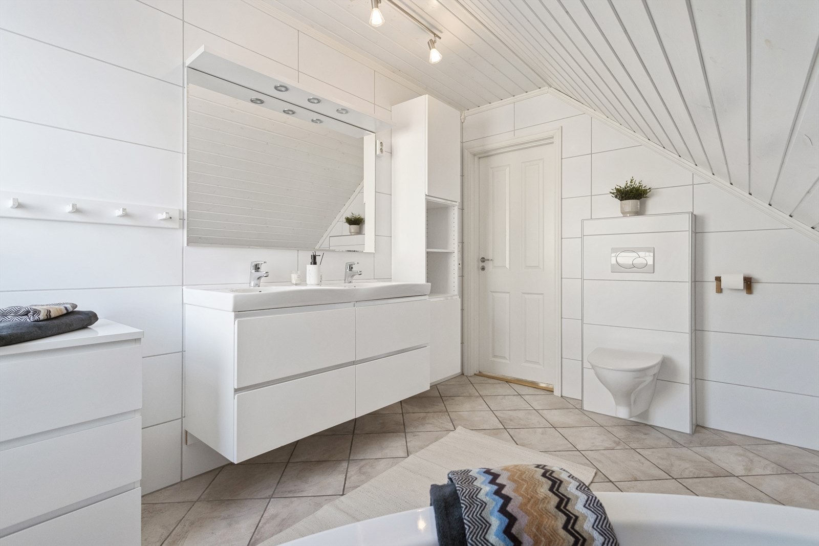 Utstyrt med servantskap, servant, veggmontert wc, badekar og mekanisk avtrekk. Galleribilde