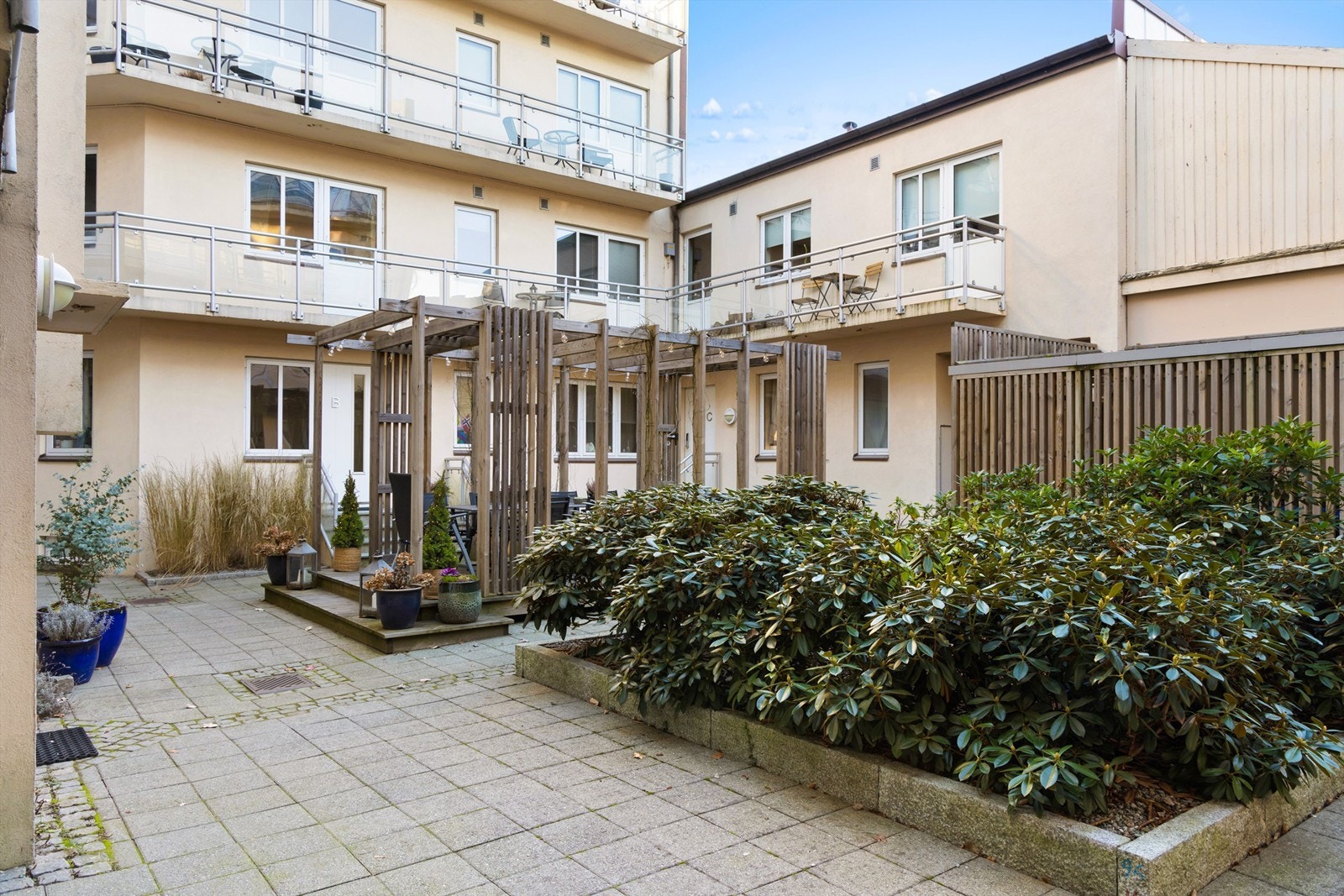 Dekorative planter og prydbusker gir gårdsrommet et grønt og inviterende uttrykk. Galleribilde