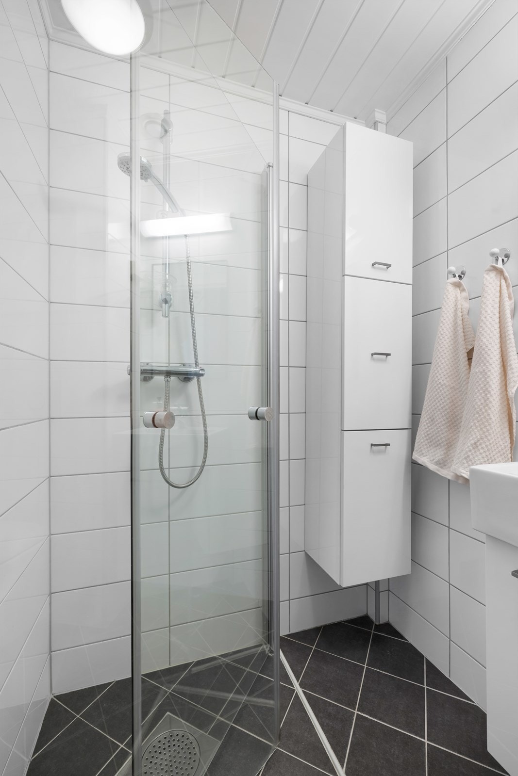 Badets areal er velutnyttet med plassbesparende dusjdører og oppbevaringsmuligheter i både servantskap og høyskap. Galleribilde