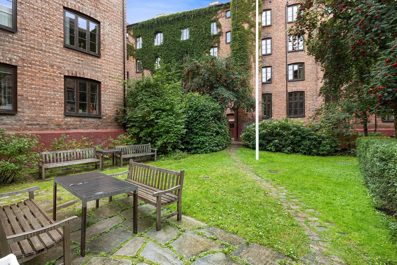 Bakgården er pent opparbeidet med plen og beplantning Galleribilde