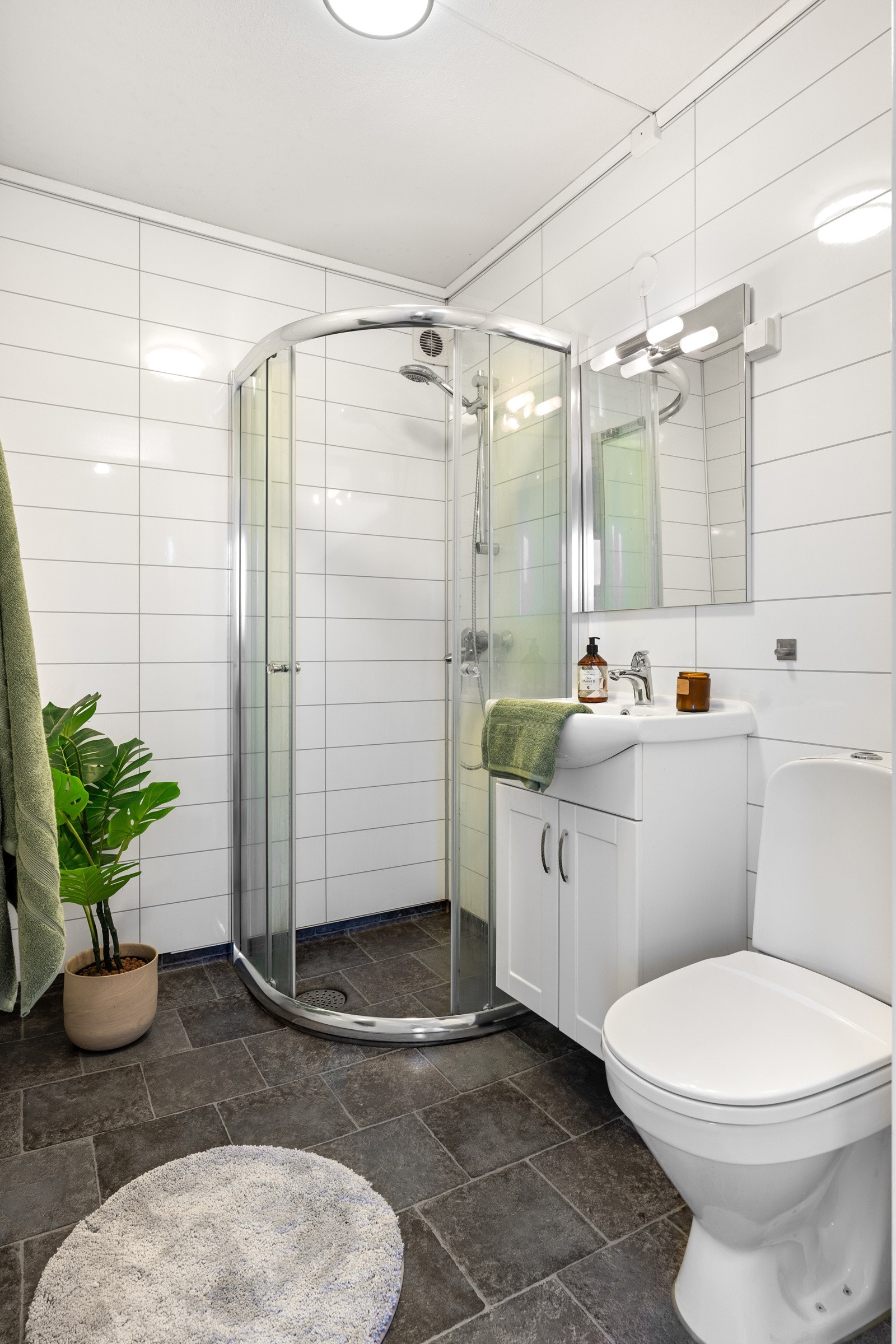 Badet er utstyrt med toalett, dusjhjørne, servant med speil og oppbevaring i underskap. Det er også opplegg for vaskemaskin på badet. Galleribilde