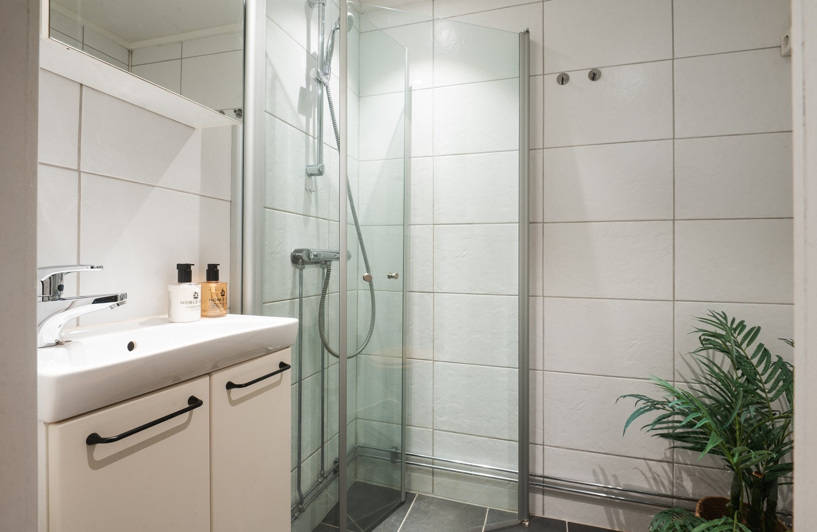 Flislagt bad med varmekabler i gulv og spotter i himling. Innfellbare glassdører til dusjsonen. Galleribilde