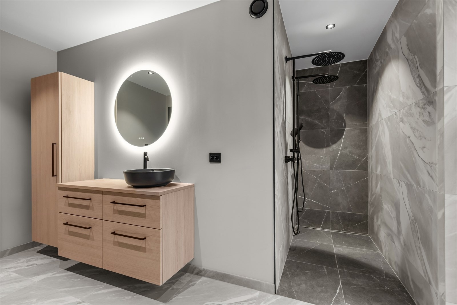 Tidsriktig rundt speil med belysning, stor dobbel dusj, vegghengt toalett og detaljer i sort utførelse. Et ypperlig familiebad med plass til hele familien! Galleribilde