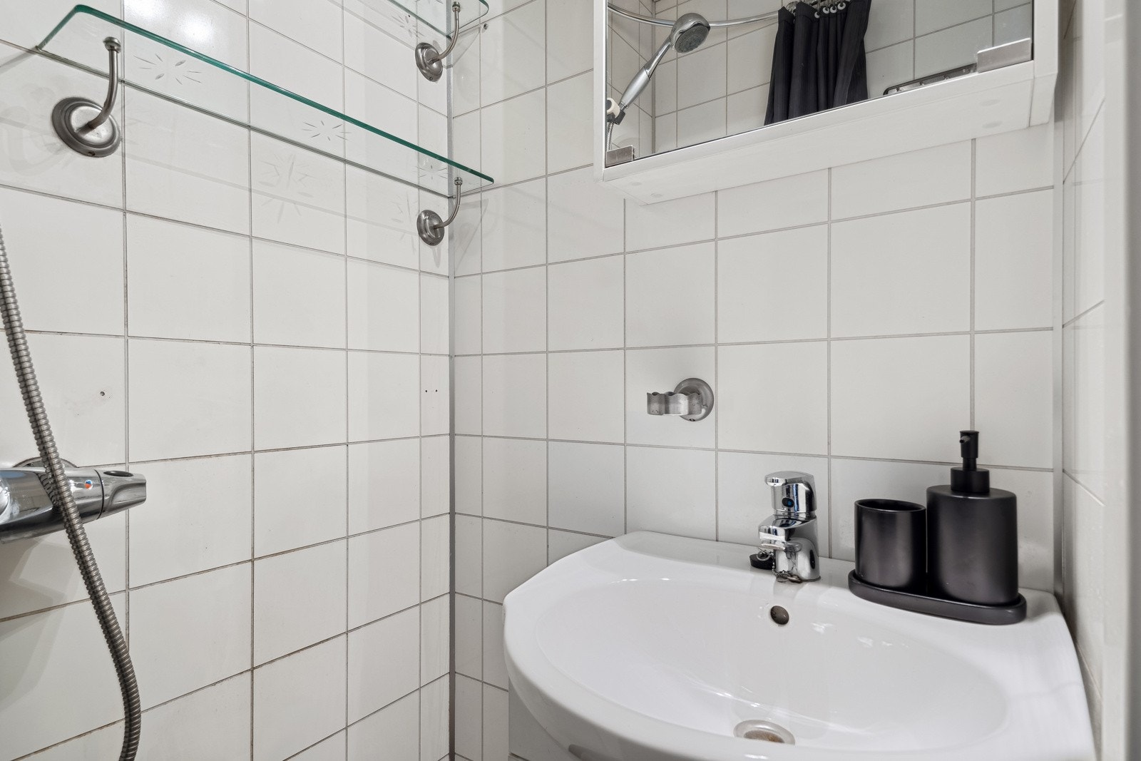 Dusj med veggforheng og servantinnredning med speil. Galleribilde