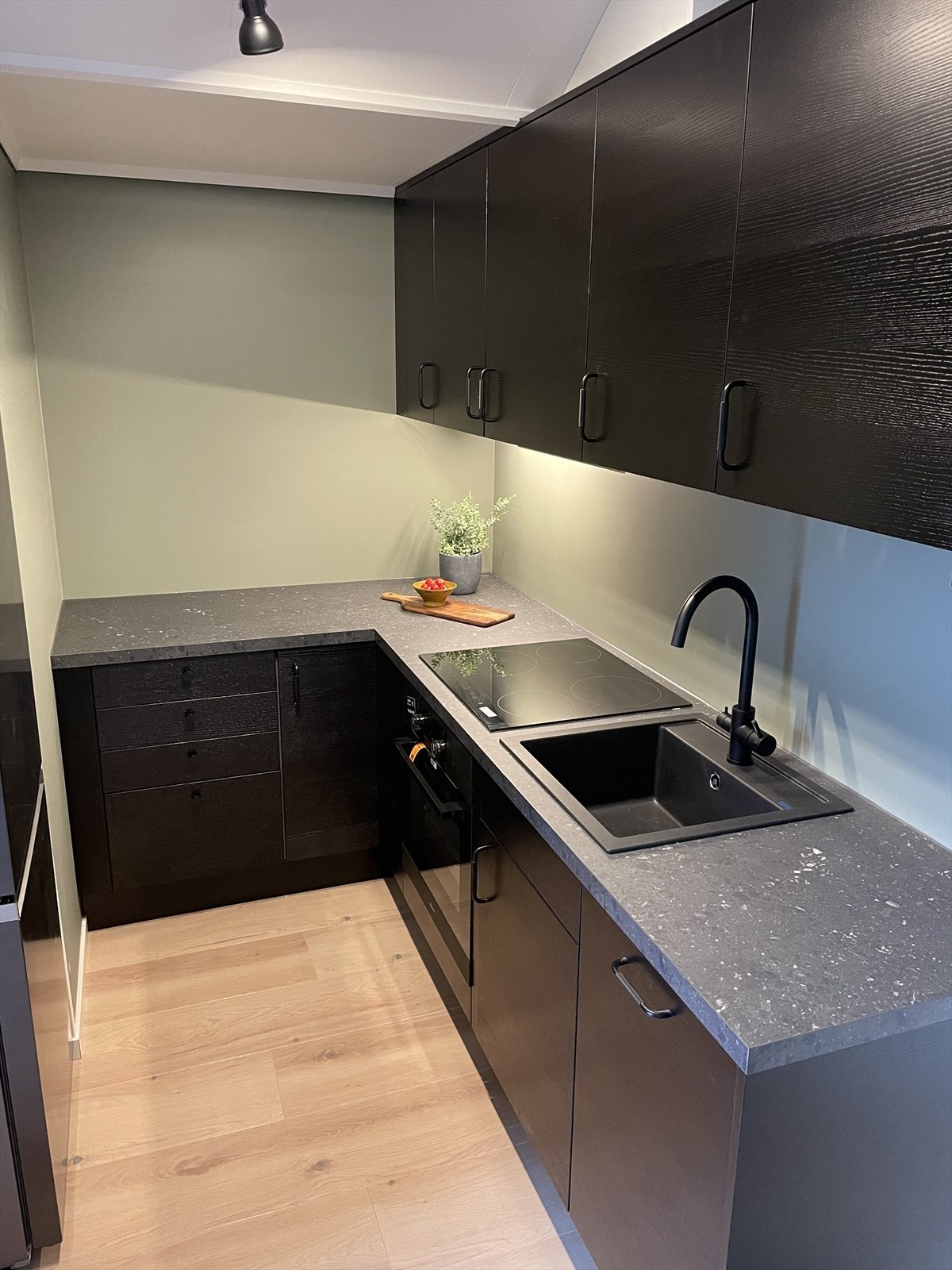 Kjøkkeninnredningen har en elegant løsning med mørke, sletter fronter, og med nedfelt vask i kompositt. Integrert oppvaskmaskin, stekeovn og platetopp. Galleribilde