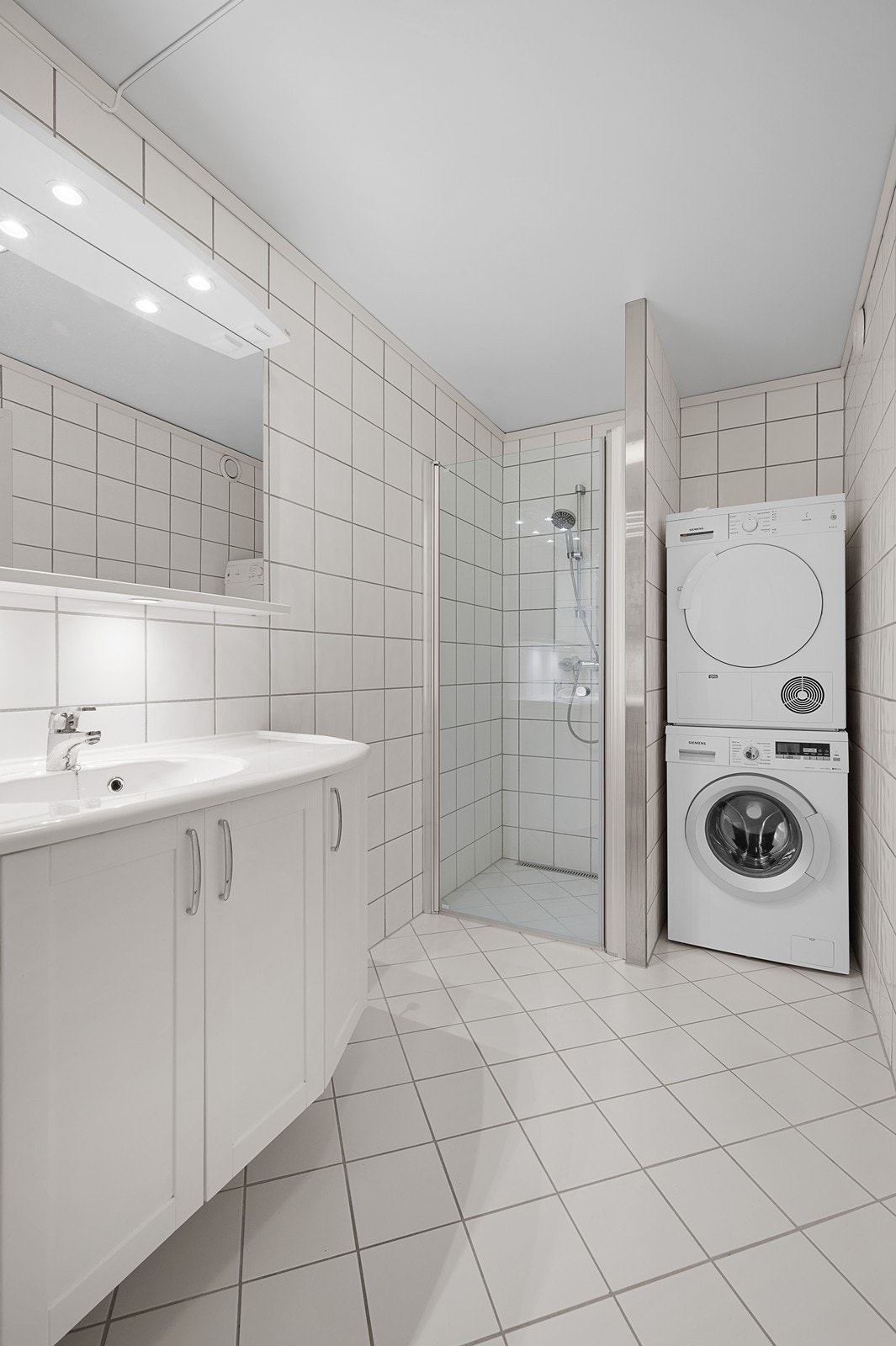 Pent bad med vegghengt wc, dusjhjørne, håndvask med speil og speilskap. Opplegg for vaskemaskin og tørketrommel. Galleribilde