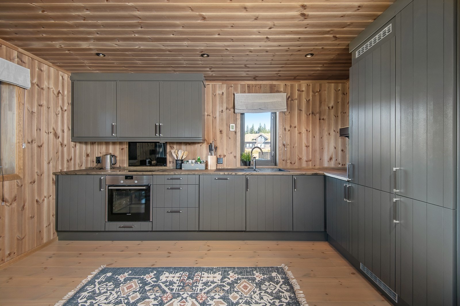 Stort og pent kjøkken i en delikat og innbydende gråtone. Integrerte hvitevarer i kjente kvalitetsmerker. Galleribilde