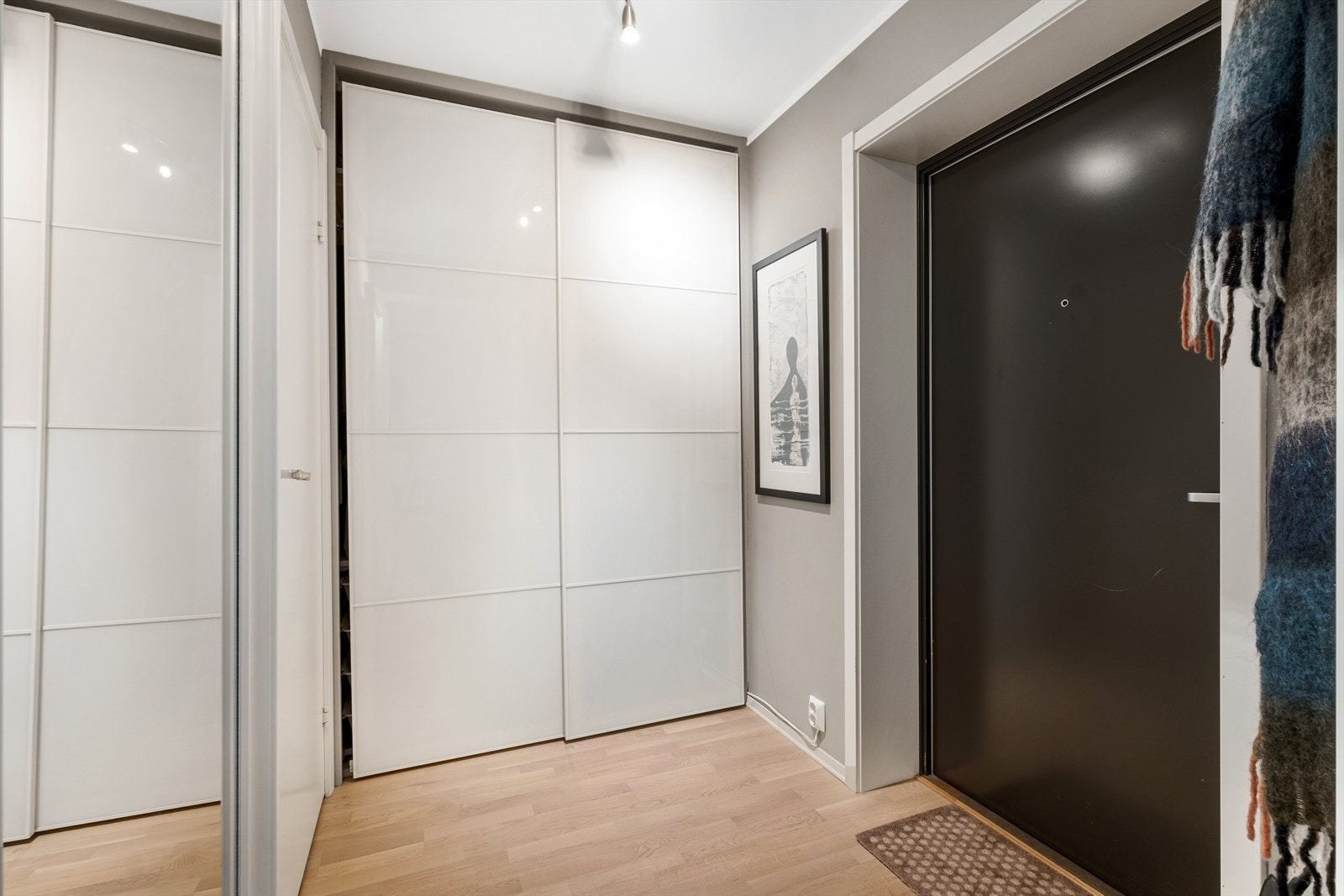 Moderne og stilren entré med parkett på gulv, som gir et godt førsteinntrykk av leiligheten. Her er det god plass til å henge fra seg ytterklær og sette fra seg sko i skyvedørsgarderobe. Galleribilde