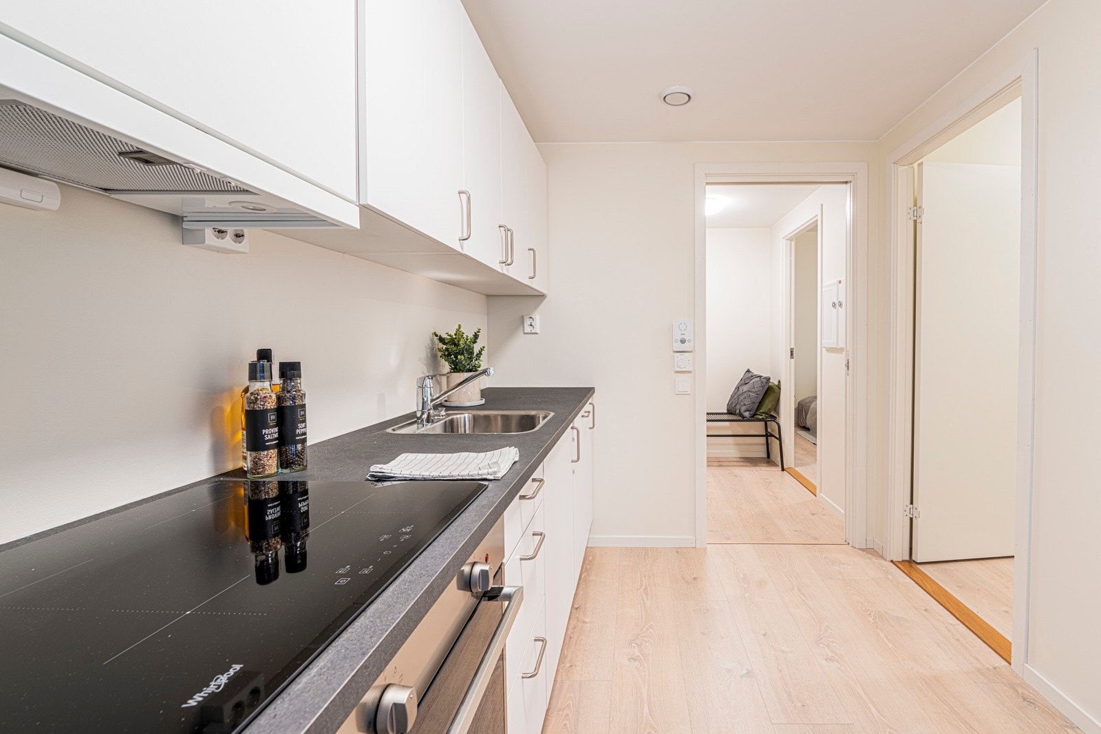 Hvit kjøkkeninnredning rikelig utbygd med over- og underskap. Galleribilde