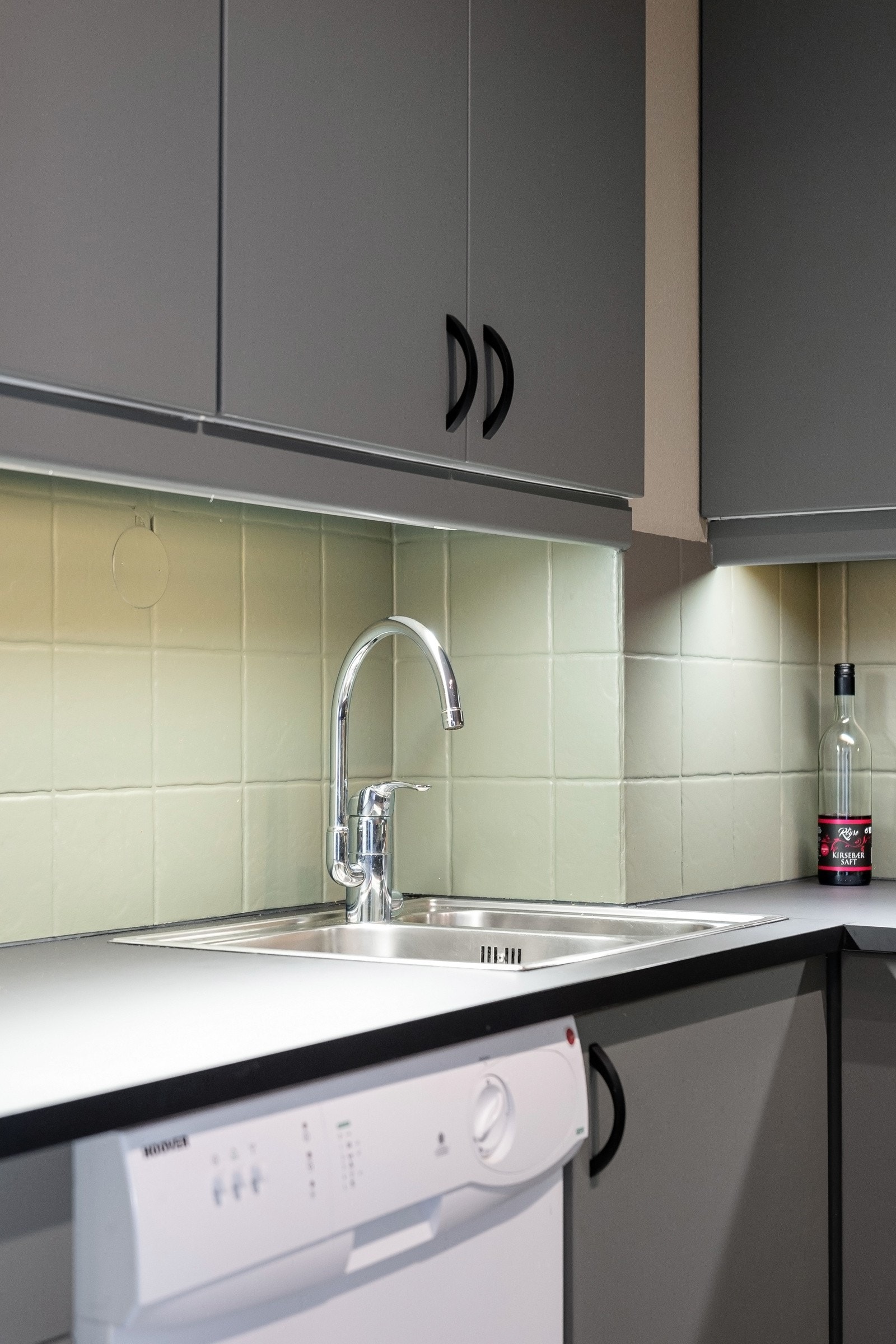 Nedfelt oppvask-/skyllekum i rustfritt stål og kjøkkenventilator over kokesone. Galleribilde