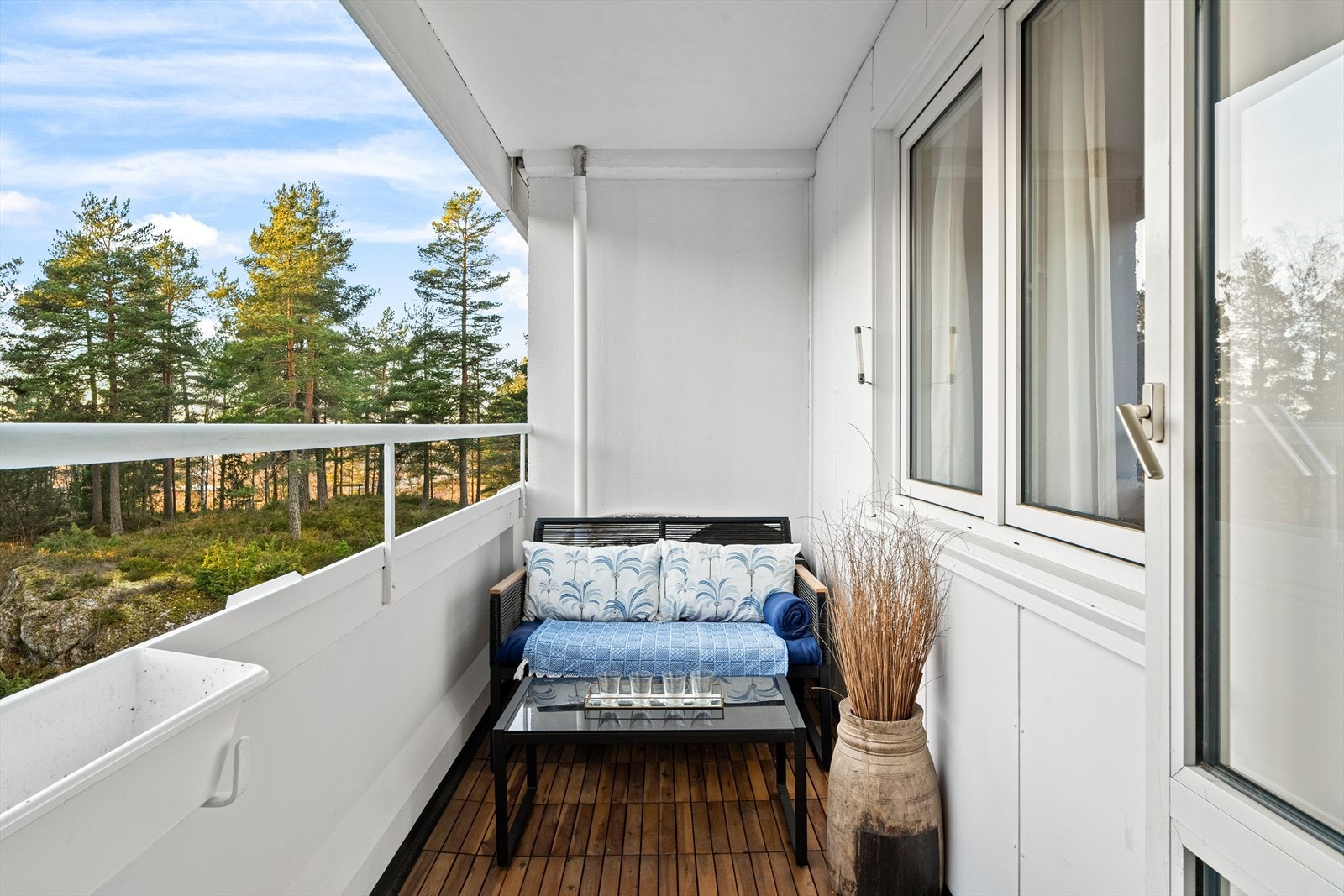 Sydvestvendt balkong på ca. 5 kvm. Betongdekke med tremmer i tre, rekkverk i metall. Galleribilde