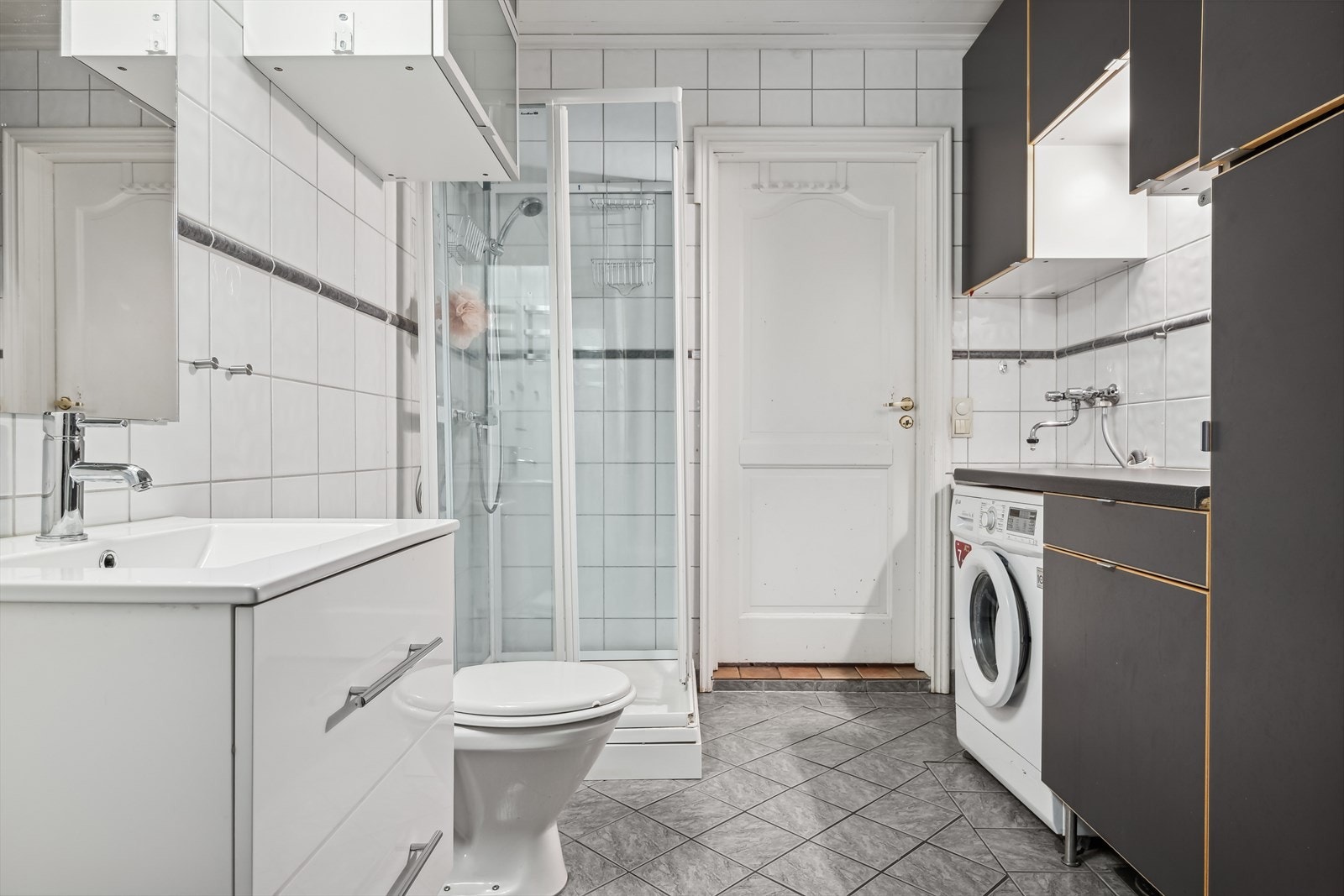 - Flislagt baderom som varmes opp ved bruk av gulvvarme. Rommet er innredet med baderomsinnredning, dusjkabinett og toalett. Opplegg for vaskemaskin - Galleribilde