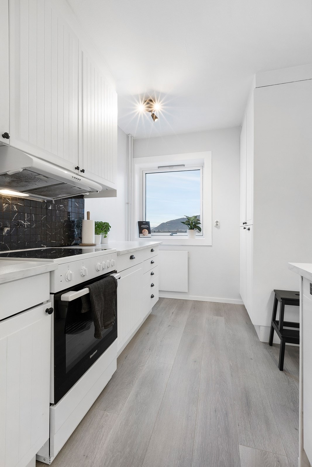 Lyst kjøkken med vindu som slipper inn mye lys. Laminat på gulv og malt mur på veggene. Galleribilde