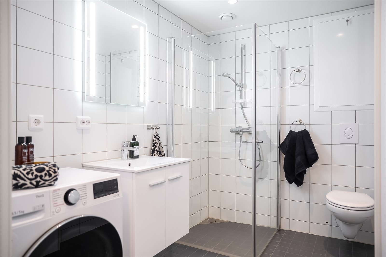 Leiligheten har et flislagt bad på 5 m². Her får du vegghengt toalett, dusjdører i glass og opplegg for vaskemaskin. Det er også varmekabler i gulv. Galleribilde