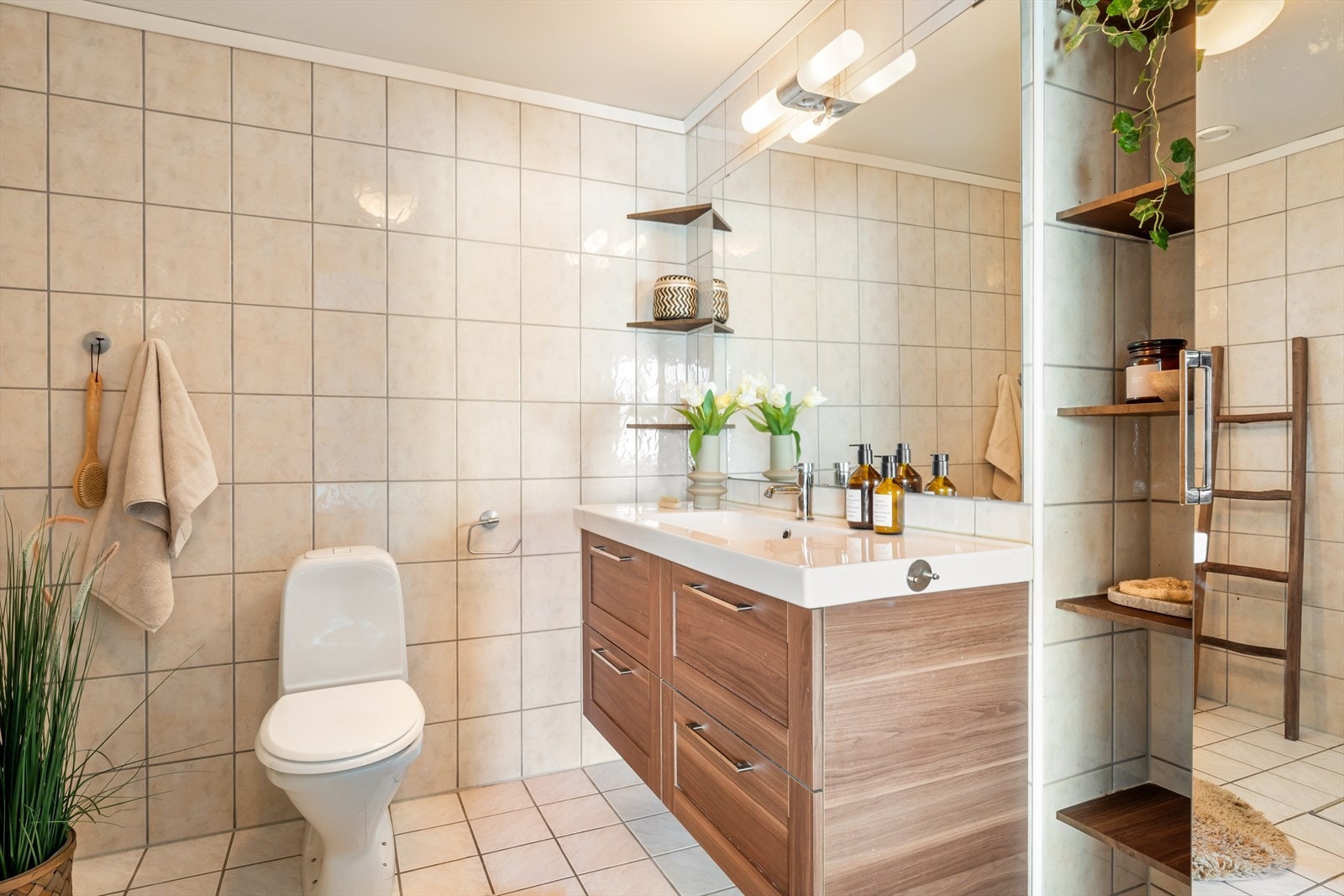 Badet har flislagte overflater og inneholder dusj, toalett og en romslig baderomsinnredning med heldekkende servant. Galleribilde
