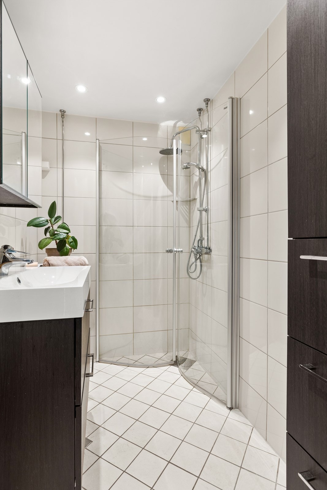 Badet har praktisk dusjhjørne, opplegg for vaskemaskin, servant med oppbevaring og varmekabler i gulv. Galleribilde