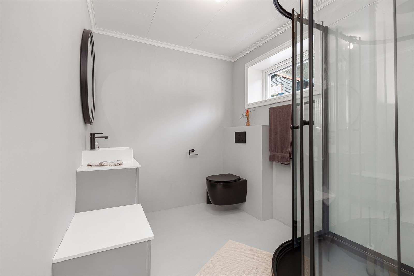 Moderne bad med microsement frå 2023 på golv og veggar. Badet er utstyrt med toalett, dusjhjørne og servant med innredning. Galleribilde