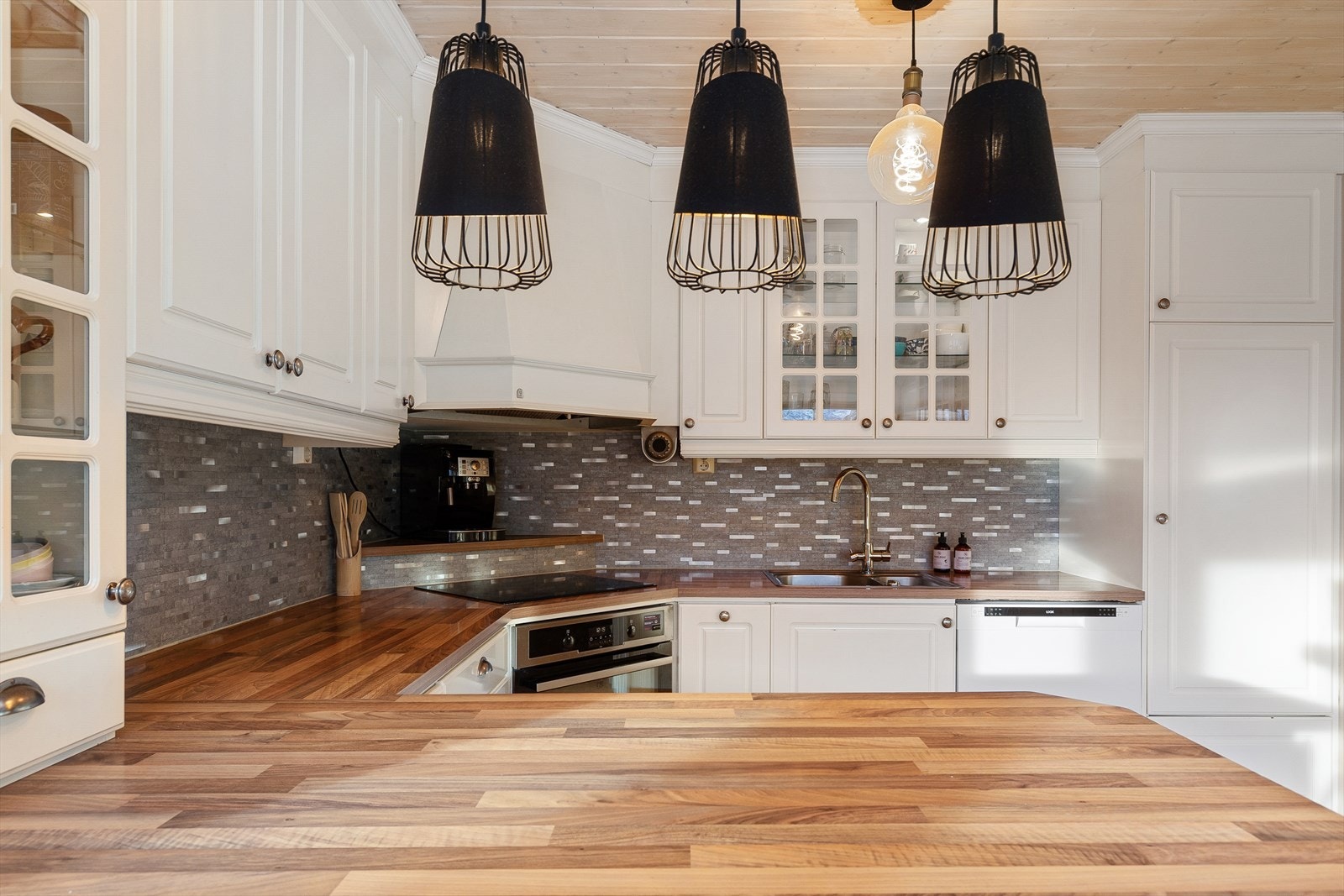 Kjøkken frå byggeår med integrert komfyr, platetopp, oppvaskmaskin og Røros ventilasjonshette. Kjøleskåp/frys er plassert i gang ved sidan av. Galleribilde