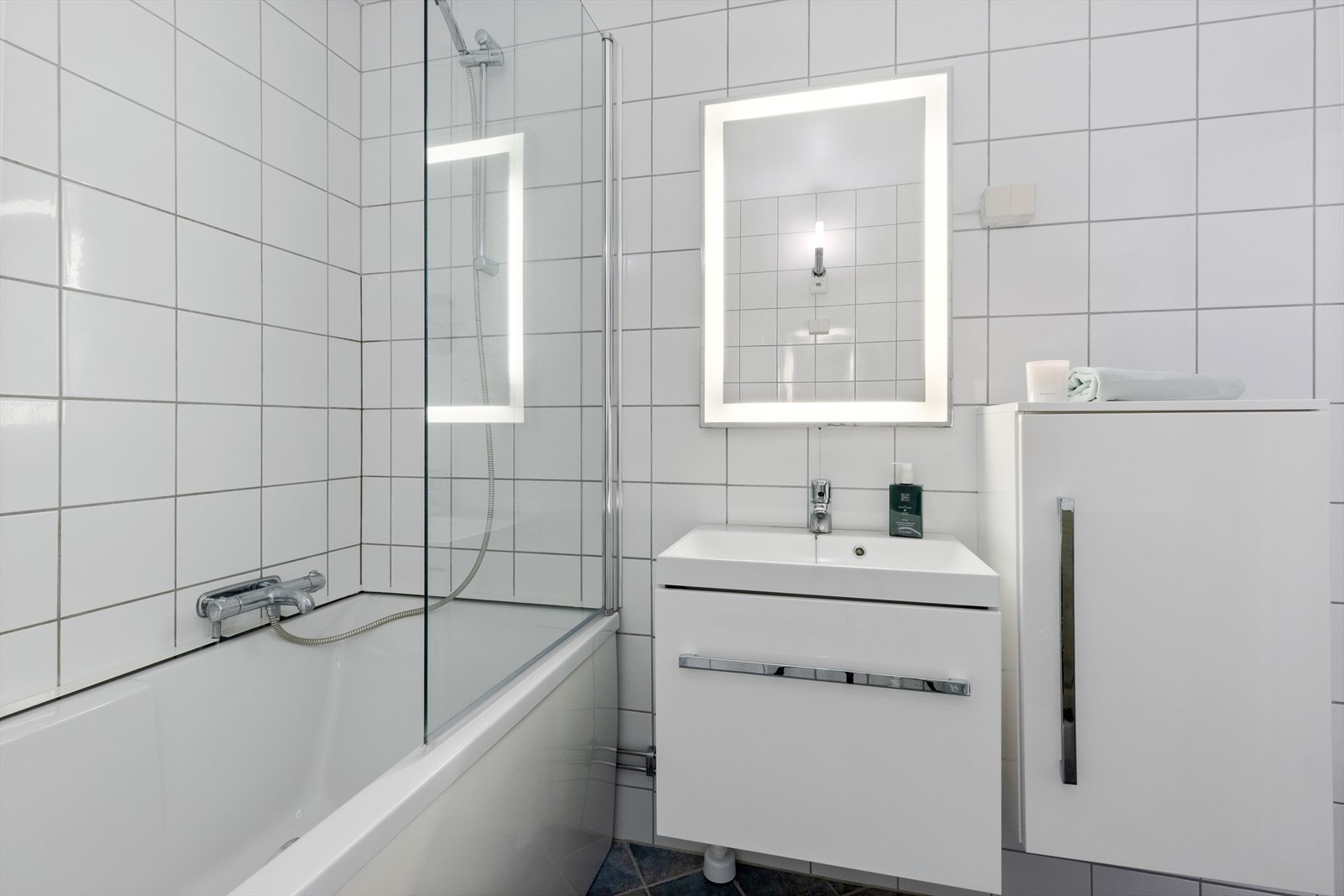 Badet er innredet med servantskap med ett-greps blandebatteri, veggskap, speil med lys, badekar, blandebatteri og dusjgarnityr. Det er opplegg for vaskemaskin. Galleribilde