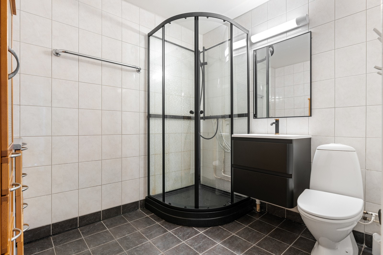 Badet måler 5 kvm og er utstyrt med toalett, dusjkabinett og en pen baderomsinnredning med skuffeseksjoner. Galleribilde