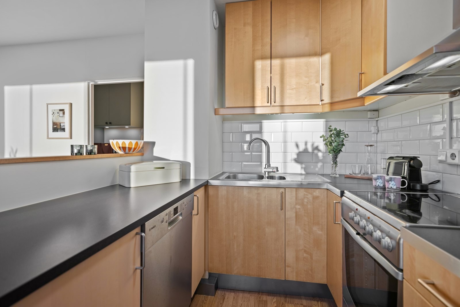 Innredning med slette finerte fronter, laminat benkeplate m/fliser over, 1 ½ oppvaskkum m/benkebeslag, kjøkkenventilator i stål antatt m/kullfilter, samt frittstående komfyr, oppvaskmaskin og kjøl-/fryseskap. Galleribilde