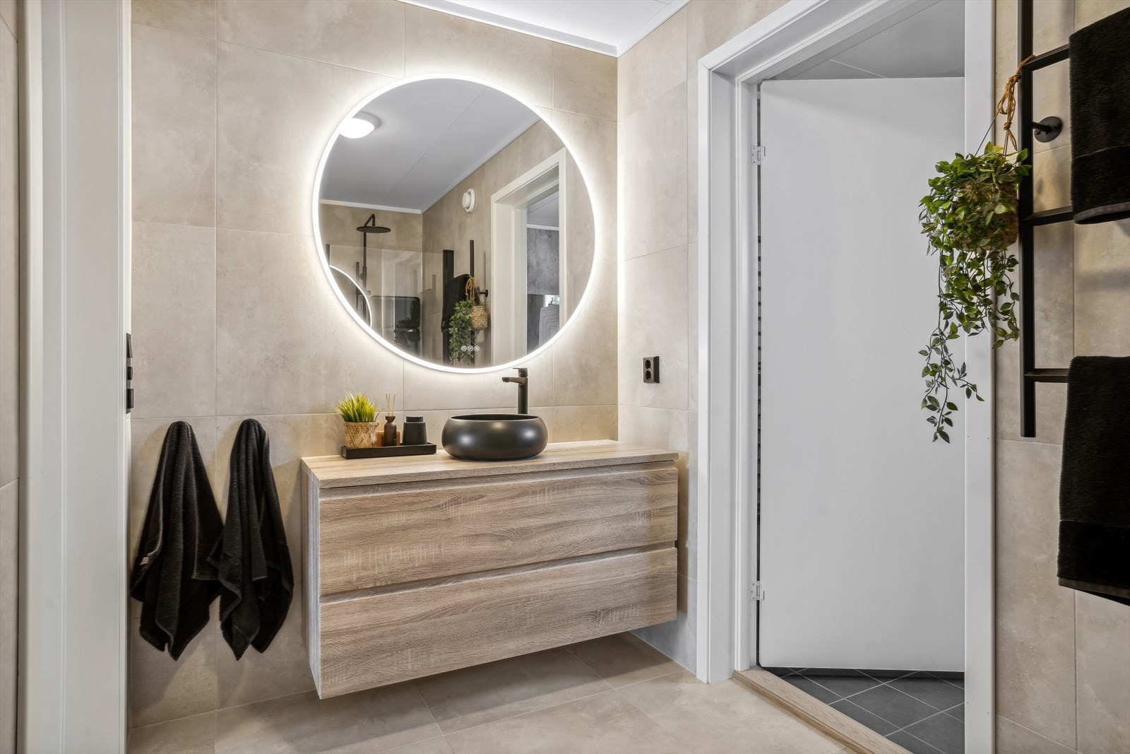 Baderommet har fliser på gulv og vegger. Også her er det varmekabler i gulv. Dusjhjørne med innfellbare glassdører, servantinnrening med tilhørende speil og lys. Galleribilde