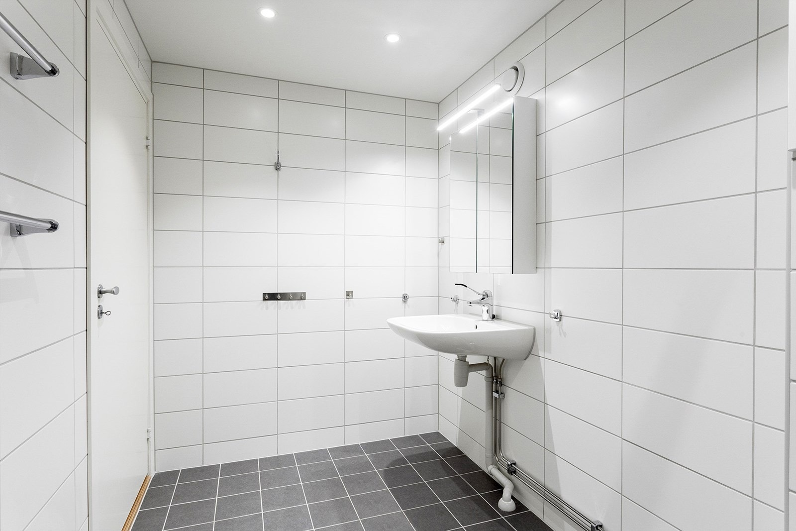 Rommet har servant, veggmontert toalett og dusjvegger/hjørne. Speilskap med lys. Det er mekanisk avtrekk Galleribilde