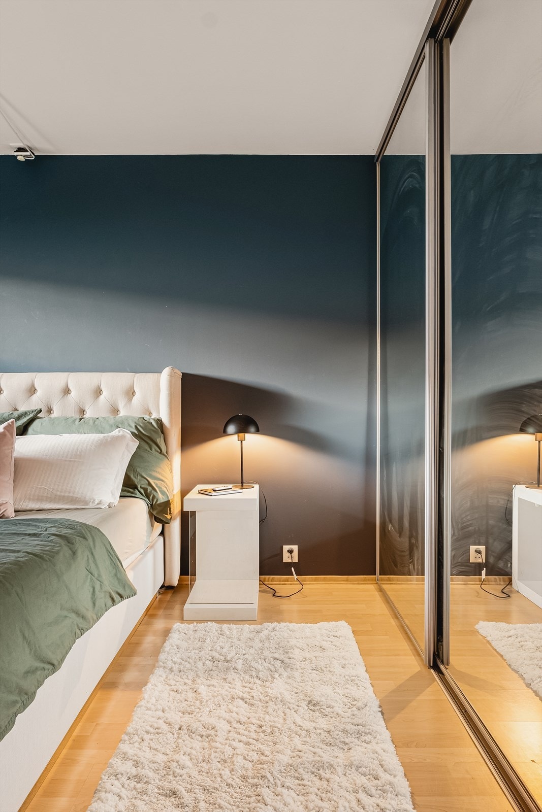 Garderobeskap i speilfronter på soverom dekker ene veggen, og gir masse plass til oppbevaring Galleribilde