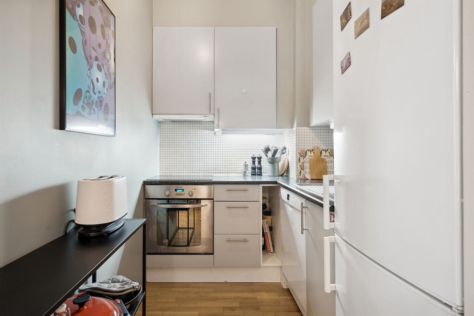 Pent kjøkken med hvite fronter og laminert benkeplate med nedfelt oppvaskkum. Galleribilde