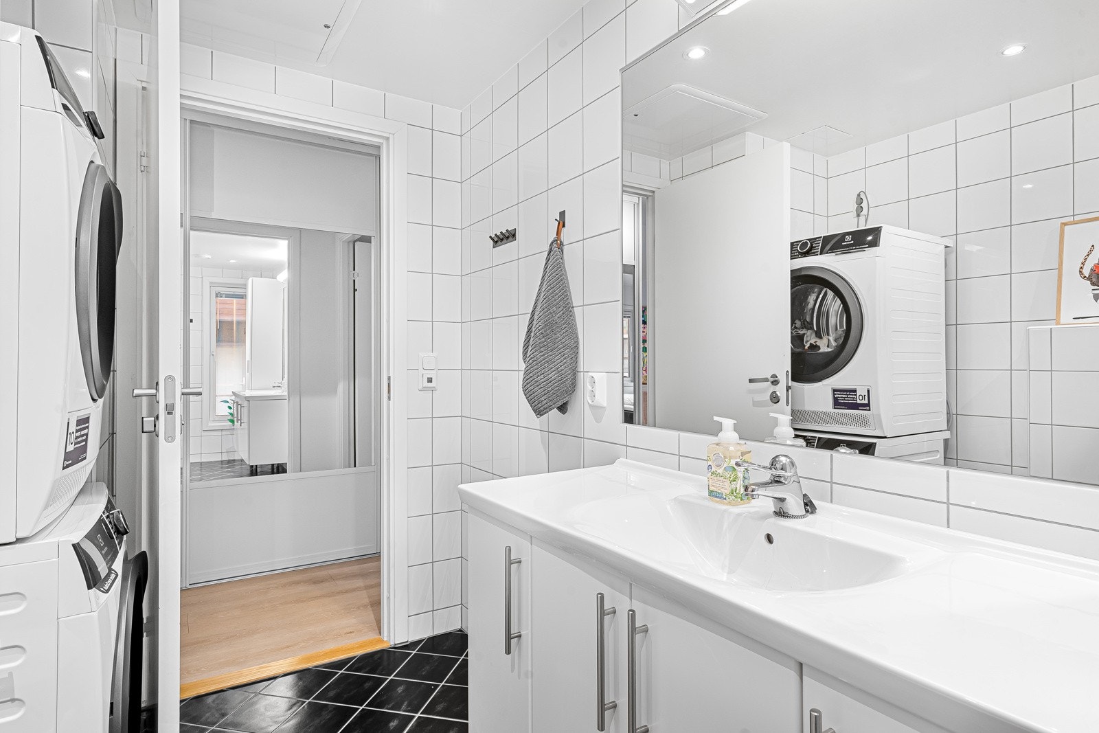 Pent, flislagt baderom med opplegg for vaskemaskin og tørketrommel. Galleribilde