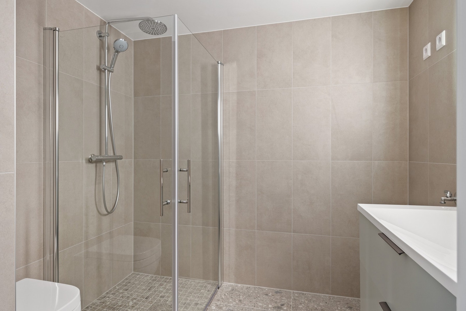 Lekkert flislagt bad med innredning og speil, dusjnisje og wc. Opplegg for vaskemaskin. Galleribilde