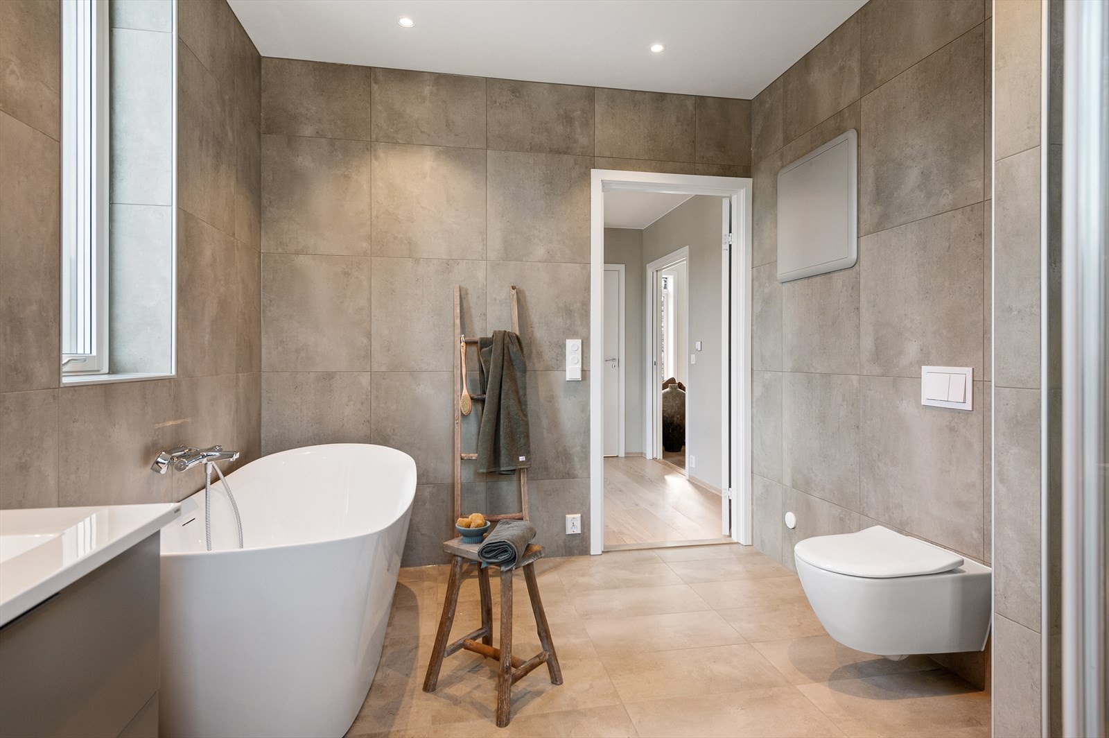 Badet har innredning med grå skuffeseksjon med dobbel servant, 2 speil med lys, veggmontert toalett og dusjhjørne med 2 regnfallsdusjer. Galleribilde