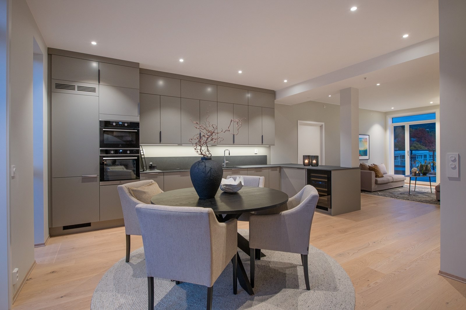 Kjøkkenet har takhøye overskap, med grå glatte fronter. Levert av Strai. Galleribilde