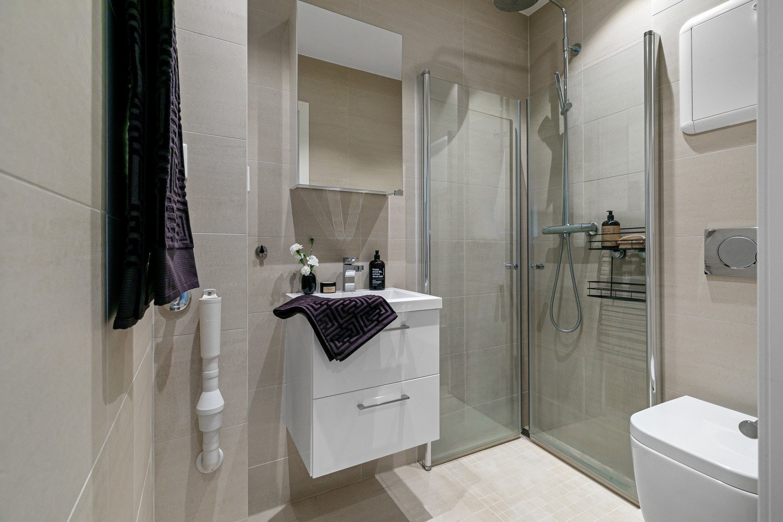 Badet har dusjsone med rainfall, veggehngt wc, servant og opplegg for vaskemaskin. Galleribilde