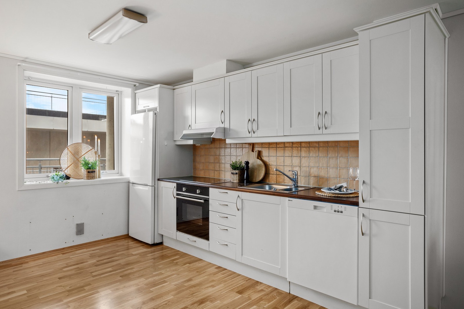 Pen innredning med integrert stekeovn, platetopp og oppvaskmaskin, samt avsatt plass for kjøleskap Galleribilde