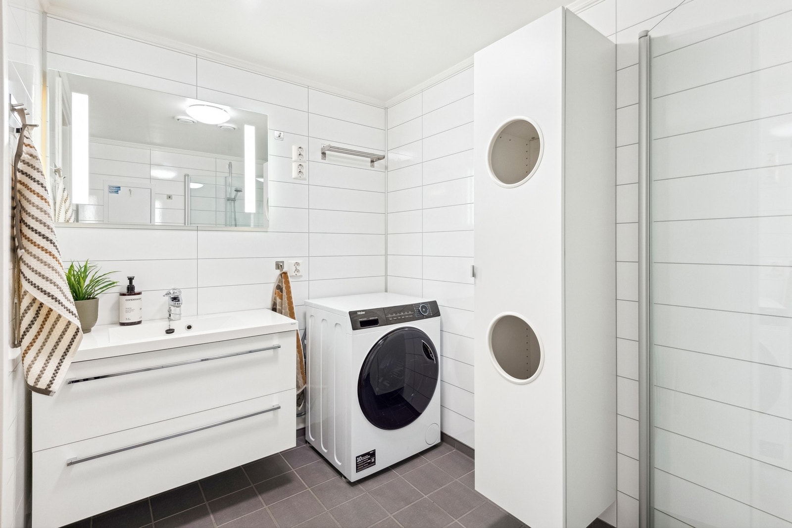 Badet har flislagt gulv med varmekabler. Det er opplegg for vaskemaskin. Galleribilde